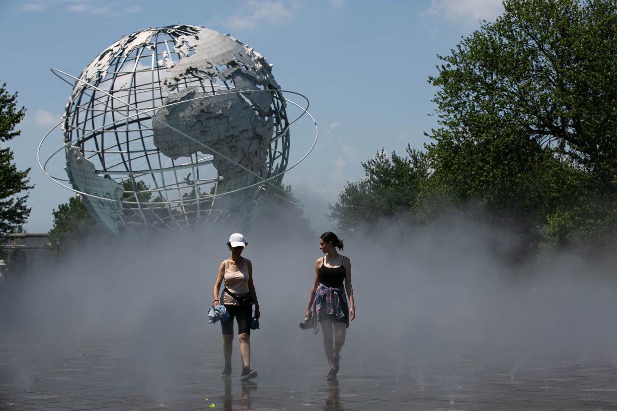 People keeping cool in a mist pathway near the Unisphere in Flushing Meadows Corona Park, Queens, New York, Thursday, July 21, 2022. 