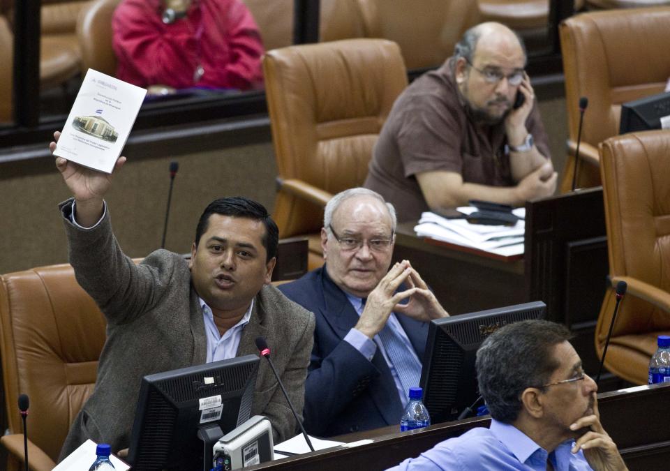 Legistlaro Wilber Lopez of the Liberal Independent Party, PLI, holds a copy of Nicaragua's Constitution as a way to show his opposition to an amendment that includes eliminating presidential term limits, at the National Assembly, Tuesday, Jan. 28, 2014, in Managua, Nicaragua. Lawmakers have approved constitutional changes that would allow President Daniel Ortega to be re-elected indefinitely, a move that his critics say is designed to keep the Sandinista leader in power for life. (AP Photo/Esteban Felix)