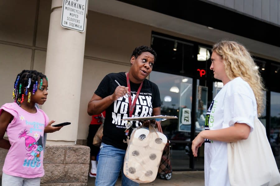 Canvasser Sienna Giraldi, 26, right, talks to Atlanta resident Makela Atchison, center, Thursday, July 20, 2023, in Atlanta. Activists with the Stop Cop City Vote Coalition are trying to get the signatures of more than 70,000 Atlanta residents by Aug. 14 to force a referendum allowing voters to decide the fate of a proposed police and firefighter training center. (AP Photo/Brynn Anderson)