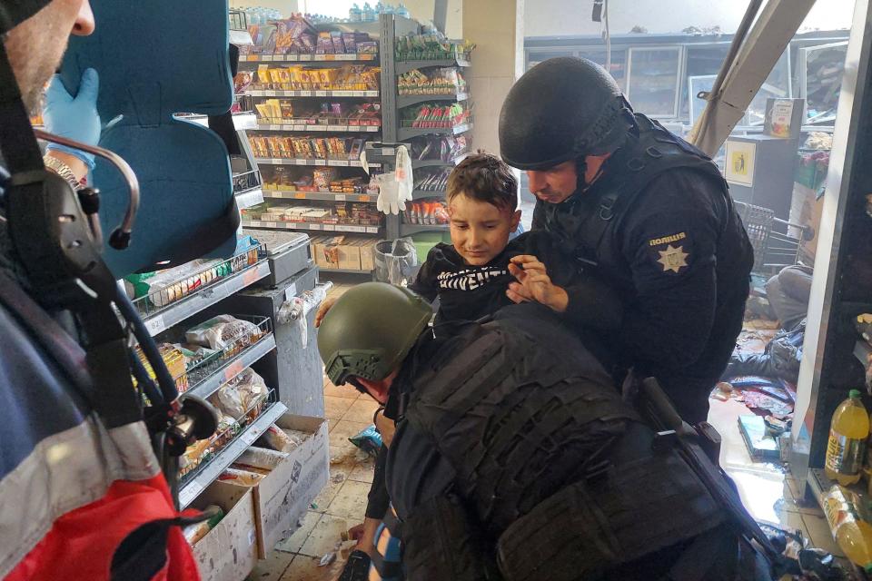 A wounded child is helped by police officers at a supermarket following a Russian strike in the southern Ukrainian city of Kherson, May 3, 2023, amid Russia's invasion of Ukraine. / Credit: DINA PLETENCHUK/AFP/Getty