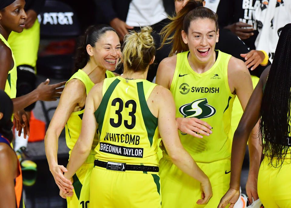 Sue Bird, Sami Whitcomb and Breanna Stewart in yellow Storm uniforms smile and celebrate. 