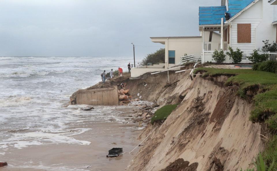 A crew uses sandbags to reinforce a dune being carved away by crashing waves ahead of Tropical Storm Nicole in the 4100 block of South Atlantic Avenue in Wilbur-by-the-Sea. Already damaged by Tropical Storm Ian, the house might not survive Nicole's impact, said Krista Goodrich, property manager for Salty Dog Vacations.