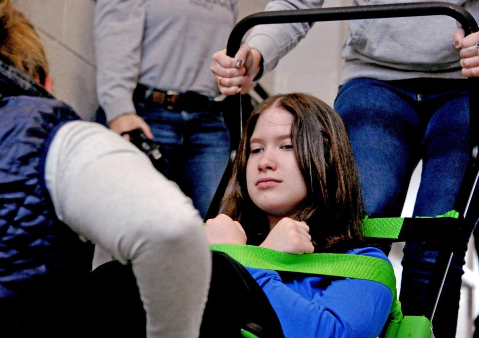 Makayla Maxwell's arms are crossed under the strap to help relieve any body tension as she is safely lowered down a flight of stairs.