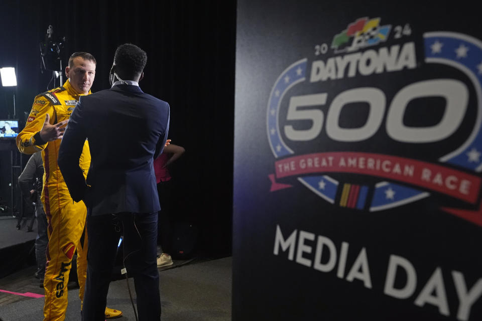 Michael McDowell, left, takes part in an interview during NASCAR Daytona 500 auto racing media day at Daytona International Speedway, Wednesday, Feb. 14, 2024, in Daytona Beach, Fla. (AP Photo/John Raoux)