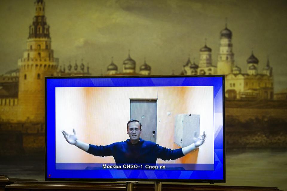 FILE - In this Jan. 28, 2021, file photo, Russian opposition leader Alexei Navalny appears on a TV screen during a court hearing appealing his jailing, with an image of the Kremlin in the background in Moscow, Russia. Navalny is serving a 2½-year prison sentence for violating parole for a conviction he says was politically motivated. In the months before the Sept. 19 parliamentary election, authorities unleashed an unprecedented crackdown on the opposition, making sure that the best-known and loudest Kremlin critics didn’t run. (AP Photo/Alexander Zemlianichenko, File)