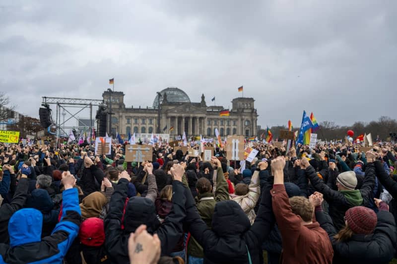Demonstrators hold up placards suring a demonstration of the alliance "We are the firewall" for democracy and against right-wing extremism in front of the Reichstag building in Berlin. Christophe Gateau/dpa