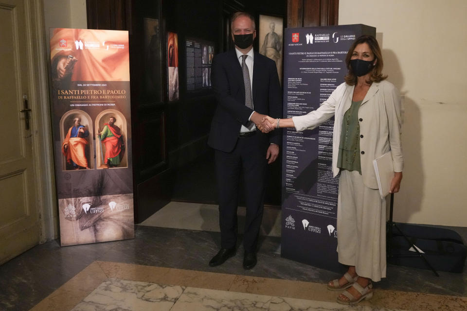 Uffizi Museum director Eike Schimidt, left, shakes hands with Vatican Museums director Barbara Jatta, at the presentation of the "St.Peter and St.Paul by Fra Bartolomeo and Raffaello" exhibition, at the Vatican Museums, at the Vatican, Friday, Sept. 24, 2021. Two restored paintings, started by Fra Bartolomeo and finished by Raffaello after his death, between 1513 and 1518, kept in the Papal Apartments and unseen by the public for decades, and the their preparatory cartoons by Fra Bartolomeo, coming from Forence's Uffizi Museum, will be on display from Sept. 25, 2021 to Jan. 9, 2022. (AP Photo/Andrew Medichini)