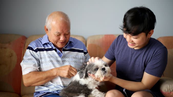 A father and son enjoying brushing dog hair and pet dog bonding session at their home.