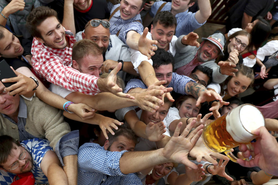 FILE - In this file photo dated Saturday, Sept. 21, 2019, people reach out for a glass of beer during the opening of the 186th 'Oktoberfest' beer festival in Munich, Germany. Bavarian officials have announced Monday May 3, 2021, they have canceled Oktoberfest festivities for the second year in a row due to concerns over the spread of the coronavirus global pandemic. (AP Photo/Matthias Schrader, FILE)