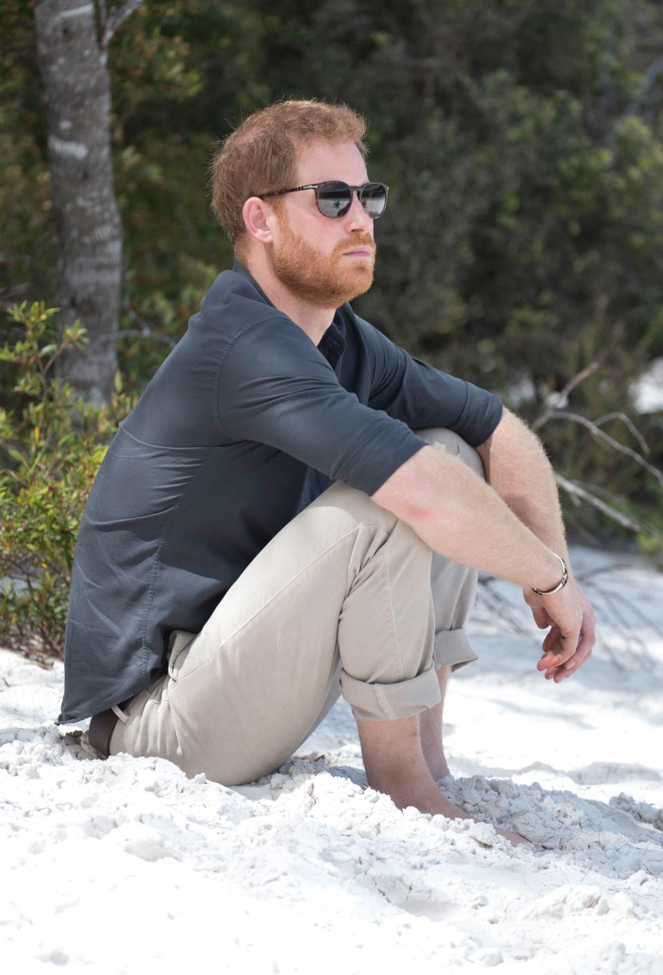 Prince Harry sitting on a beach 