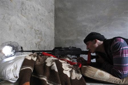 A Free Syrian Army fighter aims his weapon through a hole in a wall in Raqqa, eastern Syria November 14, 2013. REUTERS/Nour Fourat