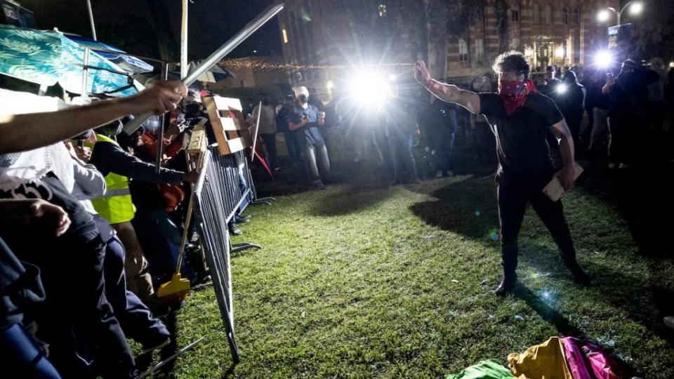 A pro-Israel counter-protester appears to spray pepper spray into the barricaded encampment of pro-Palestine student protesters at UCLA on April 30
