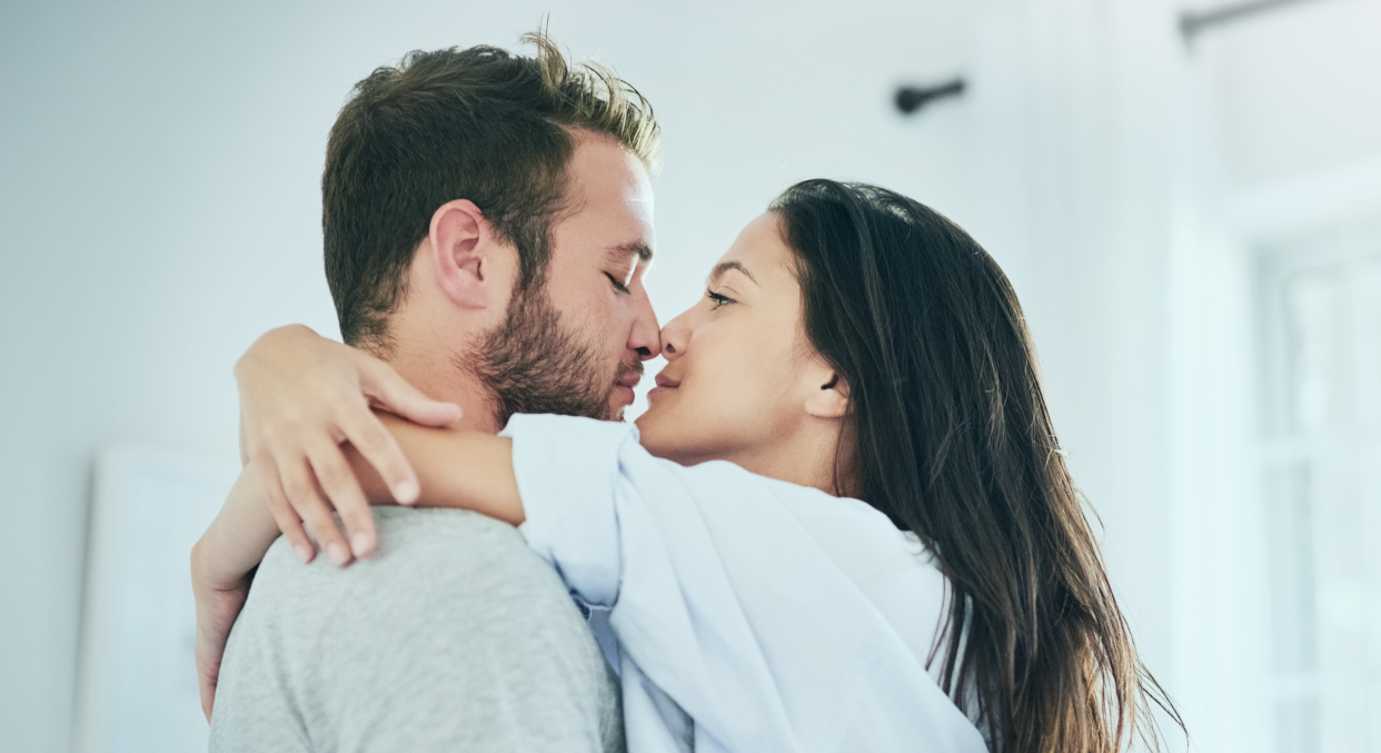 A man and woman kiss and hug at home.