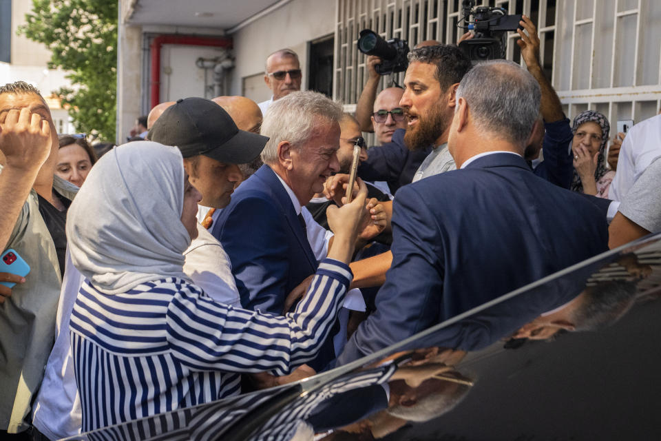 Riad Salameh, center, Lebanon's outgoing Central Bank governor, greets employees as he is escorted by bodyguards at a farewell ceremony marking the end of his 30 years in office outside the Central Bank building, in Beirut, Monday, July 31, 2023. Meanwhile, his four vice governors, led by incoming interim governor Wassim Mansouri, urged the cash-strapped country's government for fiscal reforms at a news conference in that same building. (AP Photo/Hassan Ammar)