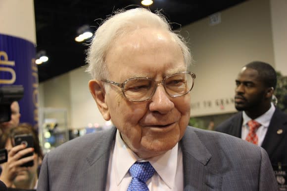 Warren Buffett smiling and walking through a crowd.