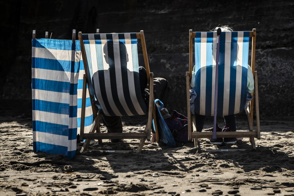 People cast shadows on to their deckchairs as they sunbath on Whitby beach in Yorkshire, as temperatures are expected to soar to 26C in some parts of the country this weekend. (Photo by Danny Lawson/PA Images via Getty Images)