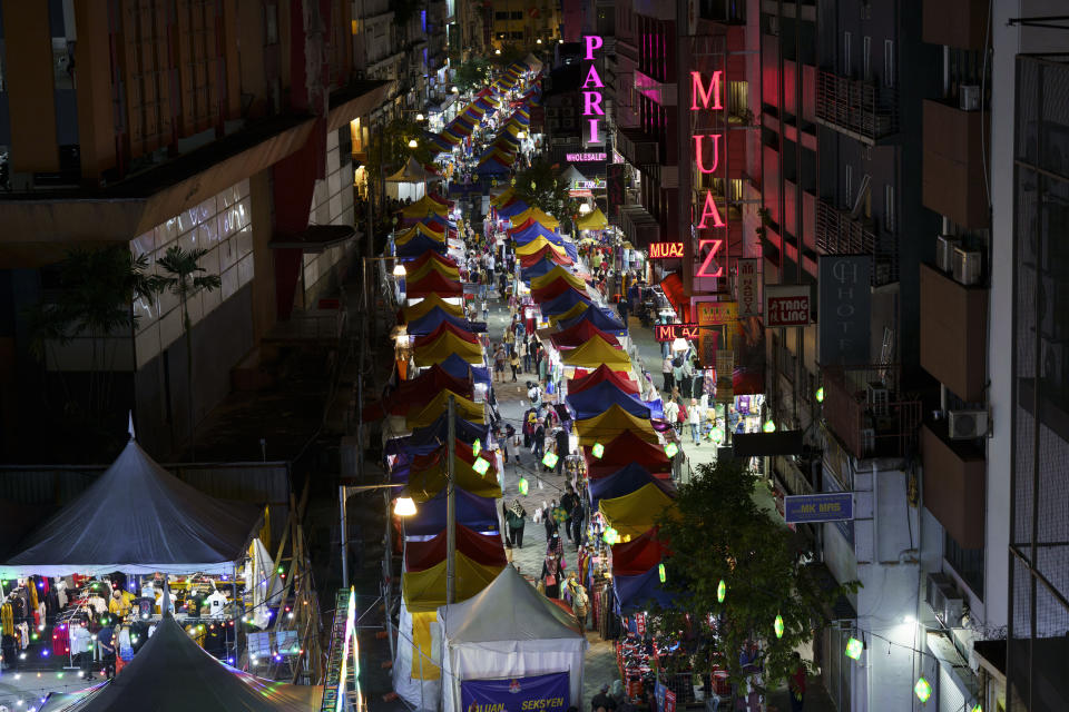 In this April 24, 2021, photo, shoppers walk through the outdoor Ramadan bazaar in Kuala Lumpur, Malaysia. Malaysian Prime Minister Muhyiddin Yassin announced Monday that the whole country will be placed under a near lockdown for about a month but all economic sectors will be allowed to operate. (AP Photo/Vincent Thian)