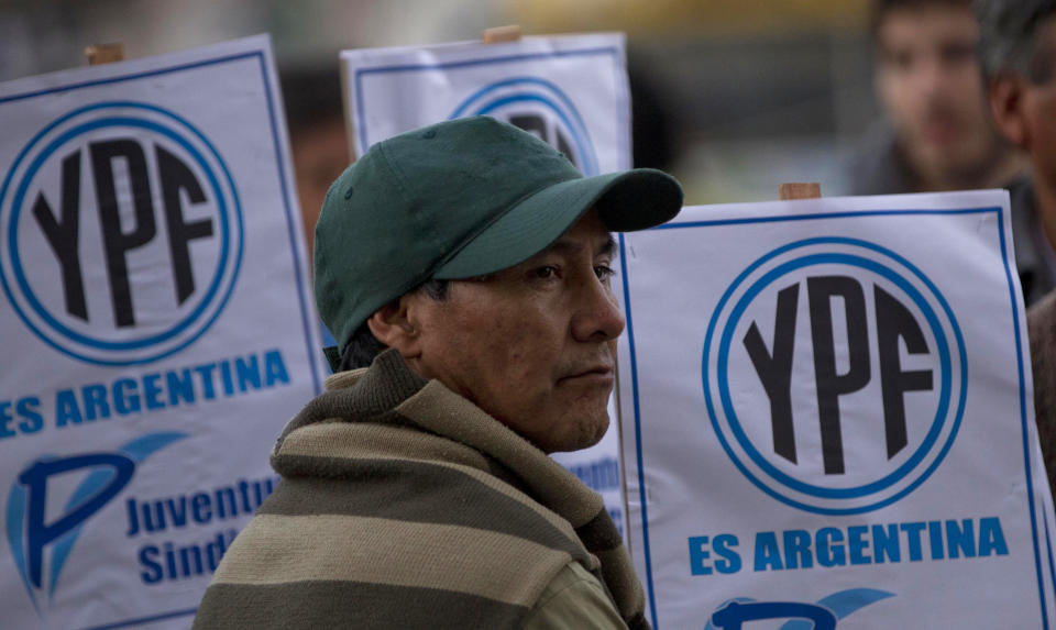 A man stands in front of signs that read in Spanish "YPF is Argentine" outside the Congress as lawmakers debate the YPF bill in Buenos Aires, Argentina, Thursday, May 3, 2012. The lower house of Argentina's congress seemed certain to give the force of law to what Argentine President Cristina Fernandez surprisingly decreed two weeks earlier: the expropriation of Repsol's $10.5 billion stake in the country's YPF oil company, without a single centavo paid in advance. (AP Photo/Natacha Pisarenko)