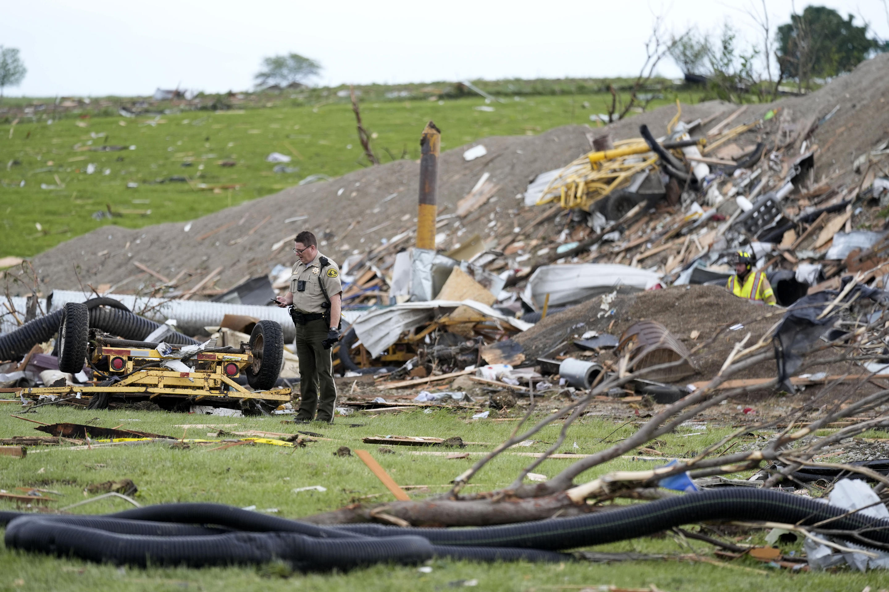 A law enforcement official stands among the remains of tornado-damaged property on Tuesday in Greenfield, Iowa.