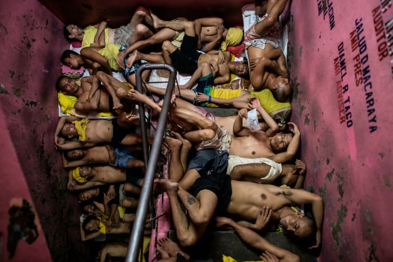 Inmates take turns to sleep on the floor of an open-air basketball court, the steps of staircases, or underneath beds