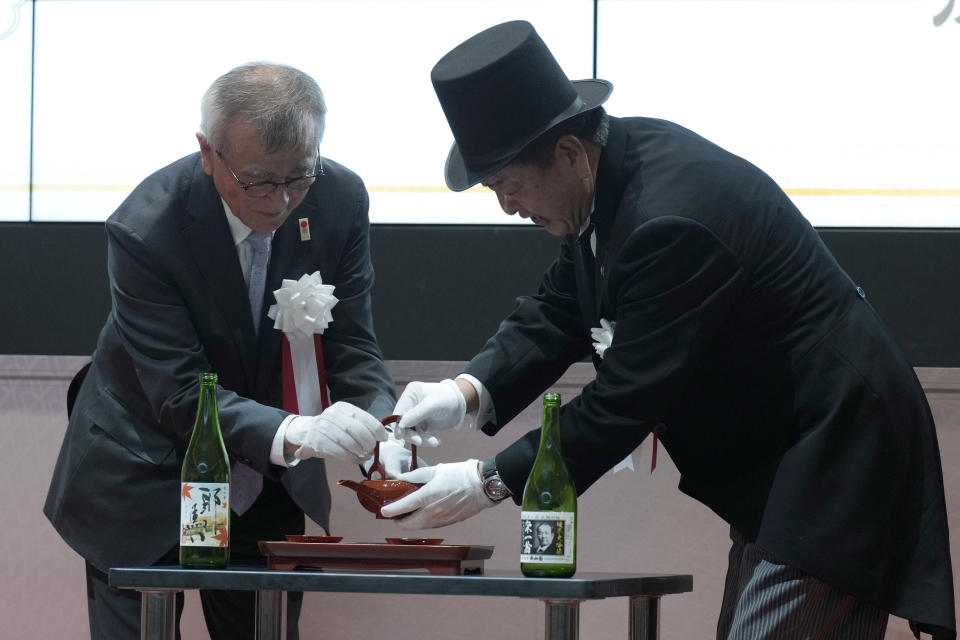 Fukaya Mayor Susumu Kojima, right, Nakatsu Mayor Masanori Okuzuka, left, perform a ceremony during the "10,000 Yen Bill Handover Ceremony" at Tokyo Stock Exchange Wednesday, July 3, 2024, in Tokyo. New 10000 yen bill featuring a portrait of Shibusawa Eiichi, the "father of Japanese capitalism.", from Fukaya city. Nakatsu city is where Yukichi Fukuzawa, a figure of previous 10000 yen bill, was from. (AP Photo/Eugene Hoshiko)