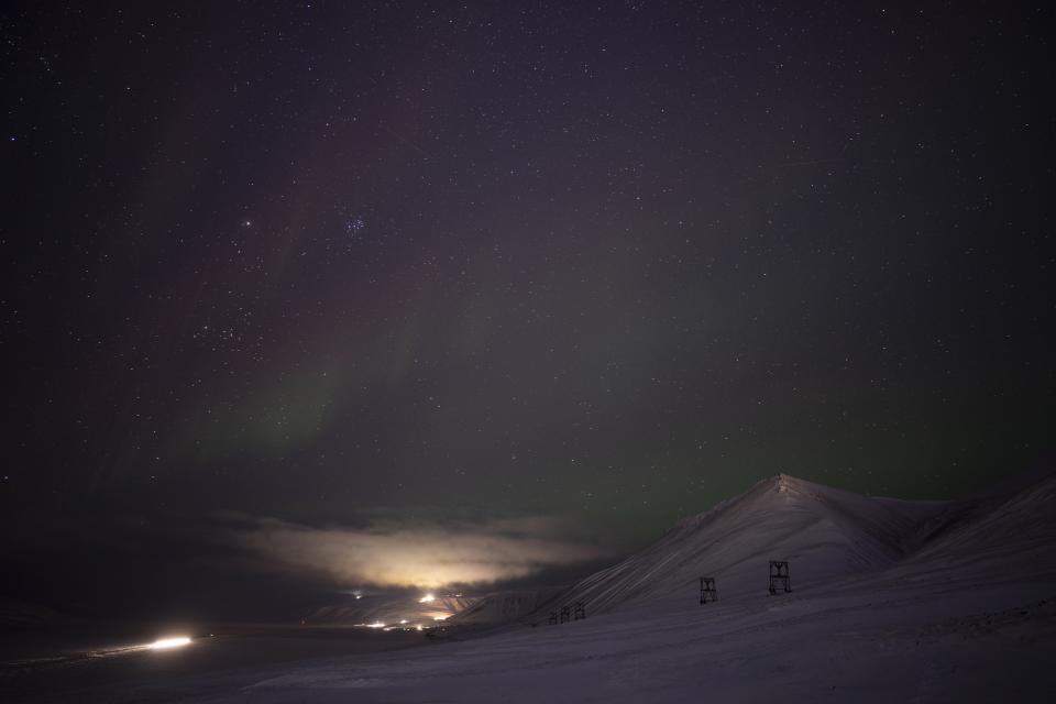 An aurora is pictured during a long exposure in Longyearbyen, Norway, Wednesday, Jan. 11, 2023. As climate change impacts the Svalbard archipelago faster and deeper than the rest of the world, its pastor is helping the community of miners and environmentalists grapple with transformation in this unforgiving, awe-inspiring wilderness. (AP Photo/Daniel Cole)