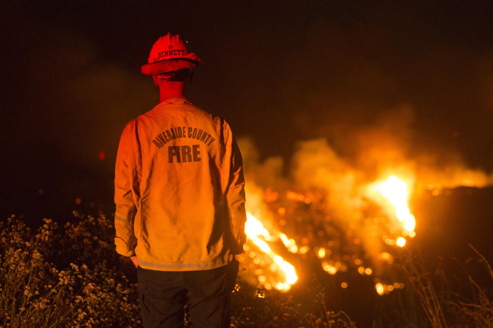A firefighter watches a brush fire at the Apple Fire in Banning, Calif., Saturday, Aug. 1, 2020. (AP Photo/Ringo H.W. Chiu)