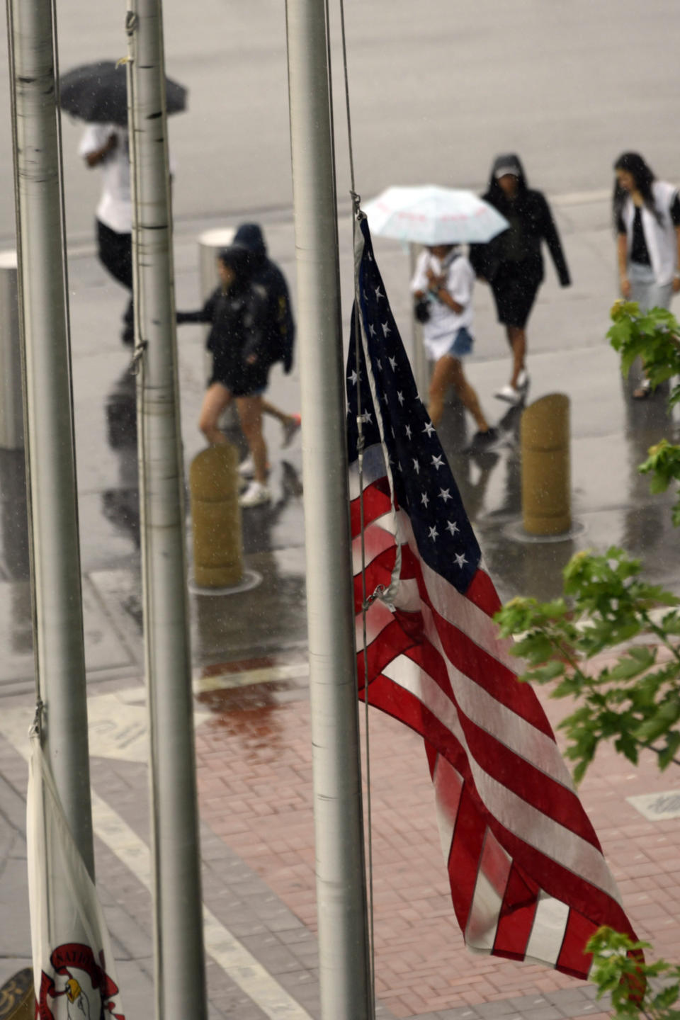 A United States flag flies at half-staff after a Fourth of July parade shooting in nearby Highland Park, Ill., while lines of fans wait to go through added security at Guaranteed Rate Field, Monday, July 4, 2022, in Chicago before a baseball game between the Chicago White Sox and the Minnesota Twins. (AP Photo/Paul Beaty)