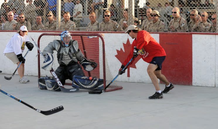 Patrice Brisebois, a National Hockey League (NHL) player and member of Team Canada scores a goal against Master-Corporal Girard of the White Team during the hockey game held by the members of Roto 01-09 of Operation ATHENA, underway at Kandahar Base during the Team Canada visit. Photo by Sgt. Ronald Duchesne, courtesy the Canadian Forces.