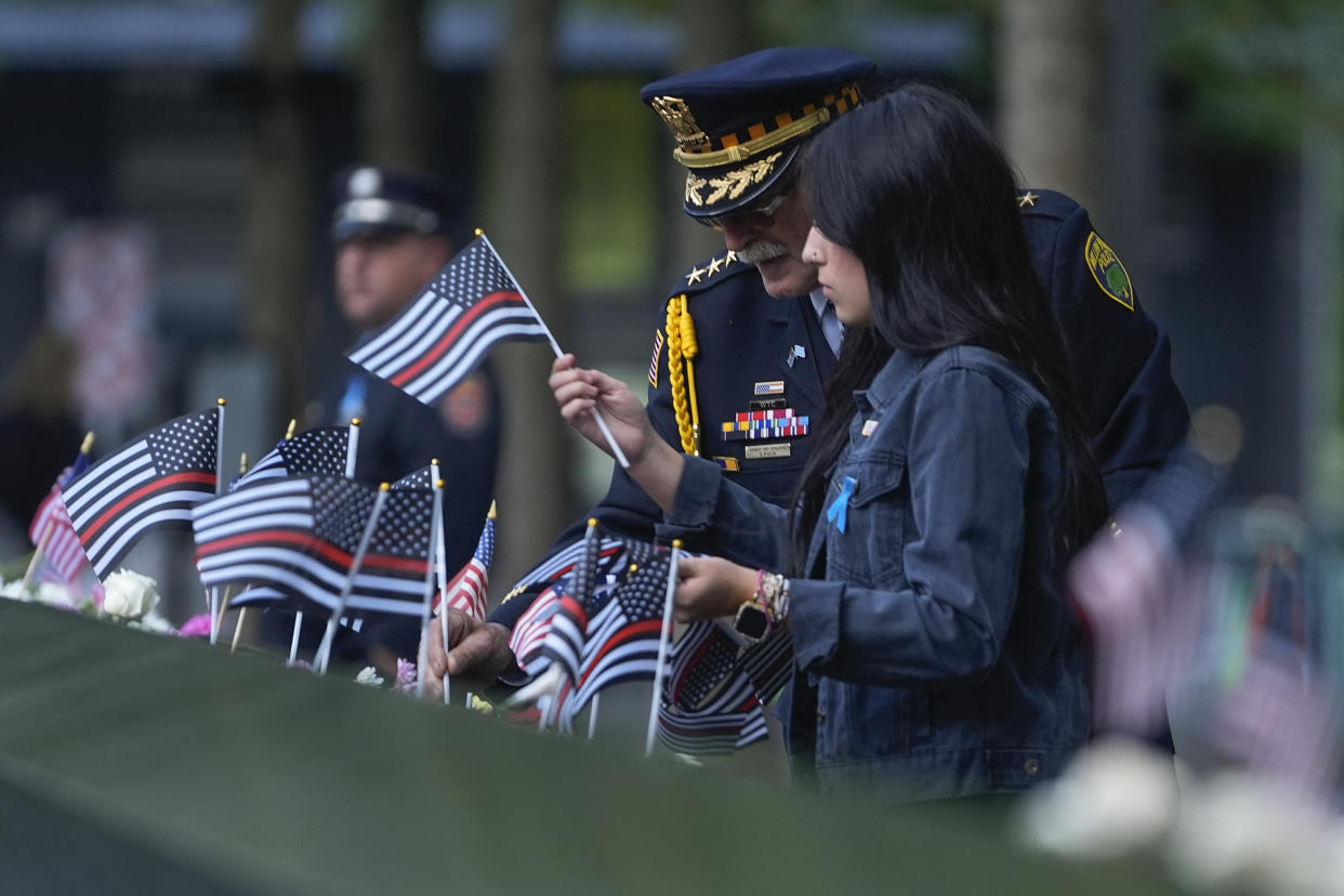 Sam Pulia, left, Willow Springs, Ill., police chief, places flags on the bronze parapets at the 9/11 Memorial on the 23rd anniversary of the Sept. 11, 2001, terrorist attacks on Wednesday in New York City.