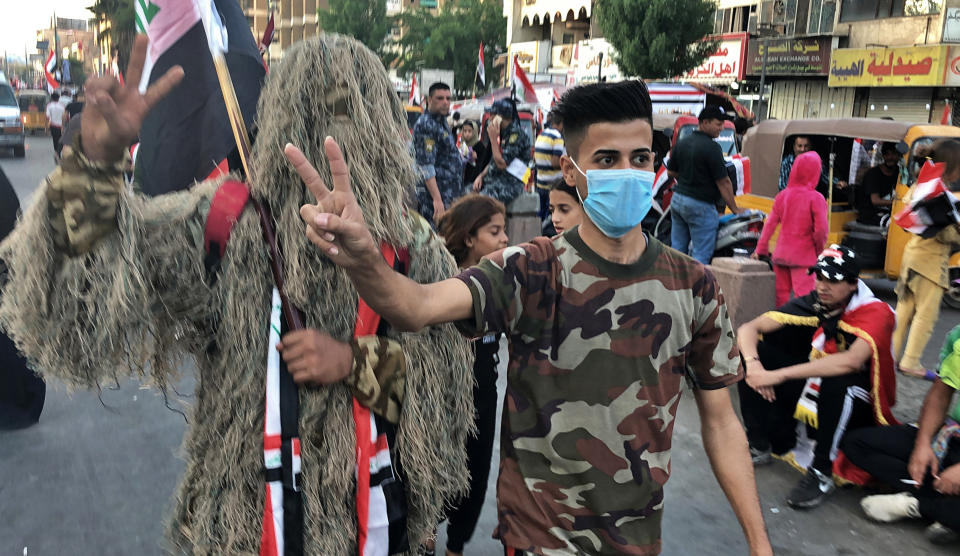 Anti-government protesters take photos with Ahmad Fadel, a protester donning a sniper uniform during ongoing protests in Baghdad, Iraq, Friday, Nov. 1, 2019. I'm wearing this uniform as a form of support to the protesters and a message to the sniper who targeted protesters "You will not scare us." Fadel said. (AP Photo/Qassim Abdul-Zahra)