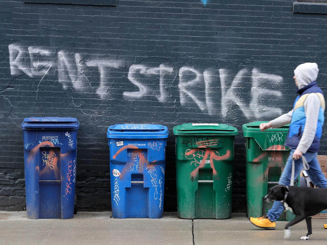 A pedestrian walks past graffiti that reads "Rent Strike" Wednesday, April 1, 2020, in Seattle, Washington.(AP Photo:Ted S. Warren)