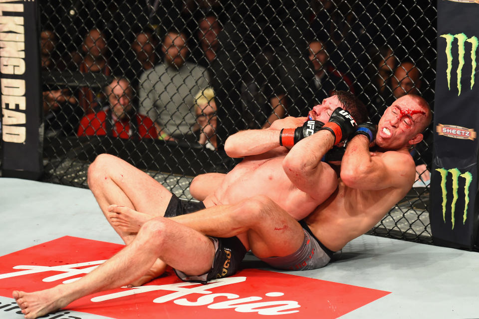 Georges St-Pierre (R) sinks in a rear-naked choke on Michael Bisping during their UFC middleweight championship bout at UFC 217. (Getty)