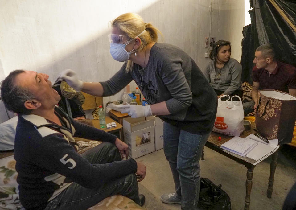 A medical worker collects a sample for COVID-19 inside a bomb shelter in Stepanakert, the separatist region of Nagorno-Karabakh, Tuesday, Oct. 20, 2020. Nagorno-Karabakh, which lies within Azerbaijan but has been under the control of ethnic Armenian forces since a war there ended in 1994, faces an outbreak of the coronavirus amid the largest outbreak of hostilities in more than a quarter-century. (AP Photo)