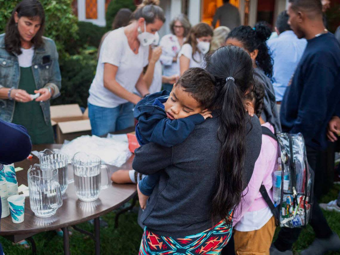 A woman, who is part of a group of immigrants flown to Martha’s Vineyard by Florida Gov. DeSantis, holds a child as they are fed outside St. Andrews Episcopal Church in Edgartown, Massachusetts.