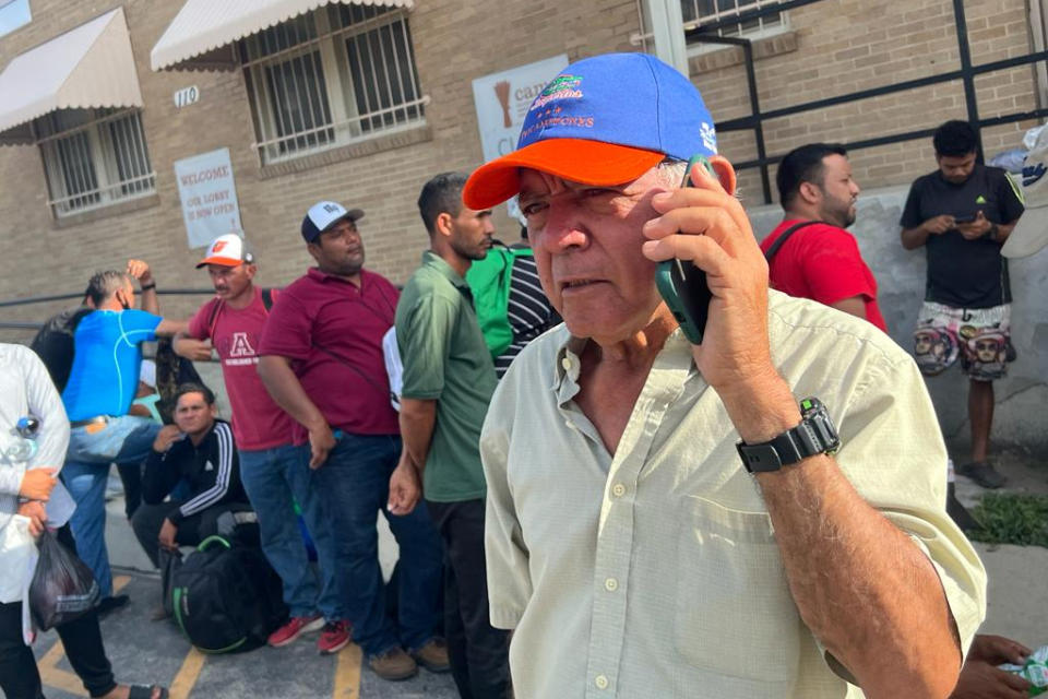 A 70-year-old Venezuelan migrant uses a cellphone as he waits online to use a shower at a homeless center in San Antonio. He says, 