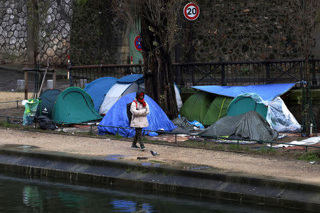 FILE PHOTO: A migrant walks next to a row of tents installed on the banks of Canal Saint-Martin in Paris, France, February 15, 2018. Picture taken 15, 2018. REUTERS/Gonzalo Fuentes/File Photo