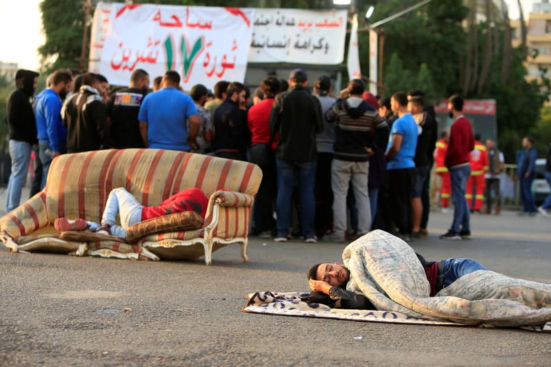 A demonstrator lies on the ground during ongoing anti-government protests, in the southern city of Sidon