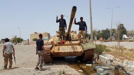 Members of the Libyan pro-government forces gesture as they stand on a tank in Benghazi, Libya, May 21, 2015. REUTERS/Stringer