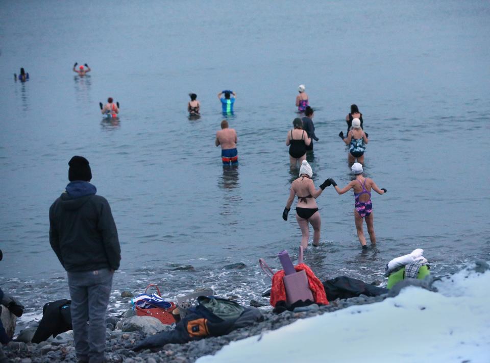 Amy Hopkins, founder of Saltwater Mountain Company, leads a group of “dippers” into the frigid water at York Harbor Beach on Jan. 19, 2024. The dippers claim that the practice boosts their mental and physical health.