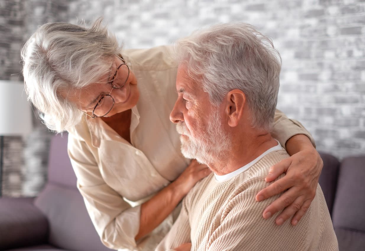 Old worried senior woman comforting her depressed, dementia, unhappy elderly man at home need medical help.