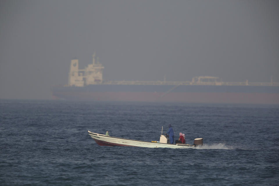 A fishing boat speeds past an oil tanker in the distance in Fujairah, United Arab Emirates, Saturday, June 15, 2019. The Kokuka Courageous, one of two oil tankers targeted in an apparent attack in the Gulf of Oman, was brought to the United Arab Emirates' eastern coast Saturday. (AP Photo/Jon Gambrell)