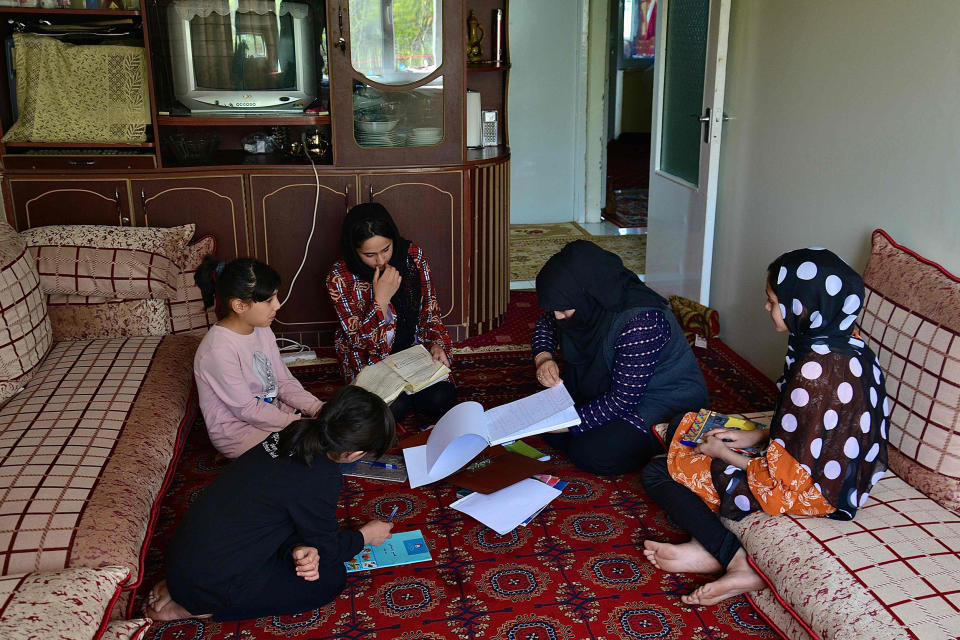 Image: School girls Malahat Haidari, right, and her sister Adeeba Haidari, center, study at their home with their younger sisters and mother  in Kabul on March 24, 2022. (Ahmad Sahel Arman / AFP - Getty Images)