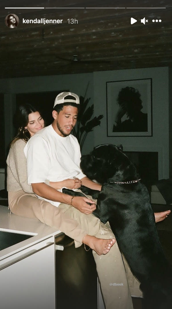 Kendall Jenner wraps her arms around Devin Booker's waist as his dog hops up on his lap