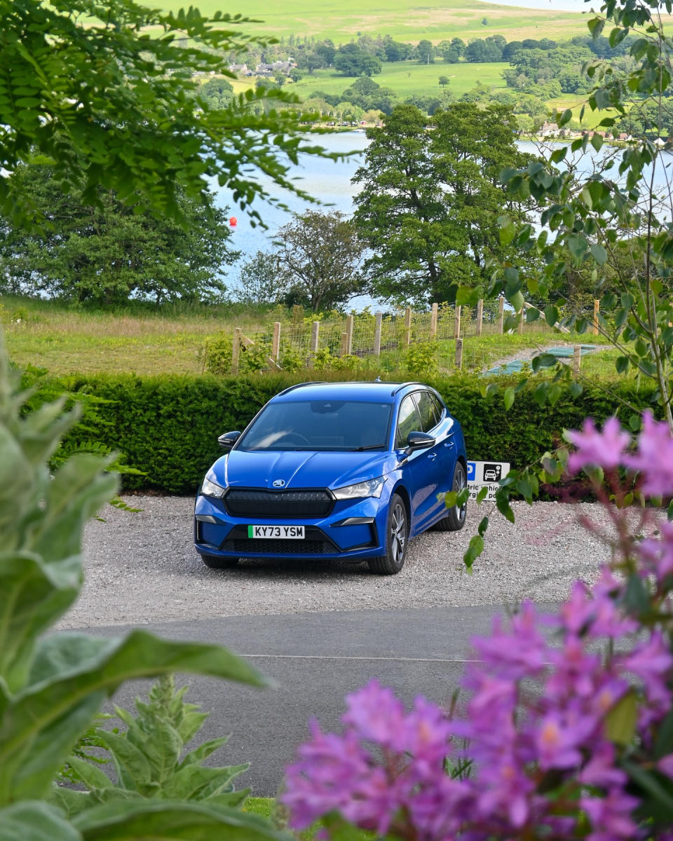 The electric car pictured charging with a beautiful country backdrop. 