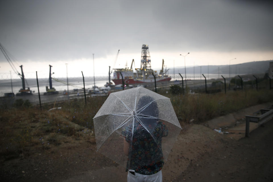 A journalist takes pictures from afar of the drilling ship 'Yavuz' scheduled to be dispatched to the Mediterranean, at the port of Dilovasi, outside Istanbul, Thursday, June 20, 2019. Turkish officials say the drillship Yavuz will be dispatched to an area off Cyprus to drill for gas. Another drillship, the Fatih, is now drilling off Cyprus' west coast at a distance of approximately 40 miles in waters where the east Mediterranean island nation has exclusive economic rights. The Cyprus government says Turkey's actions contravene international law and violate Cypriot sovereign rights. (AP Photo/Lefteris Pitarakis)