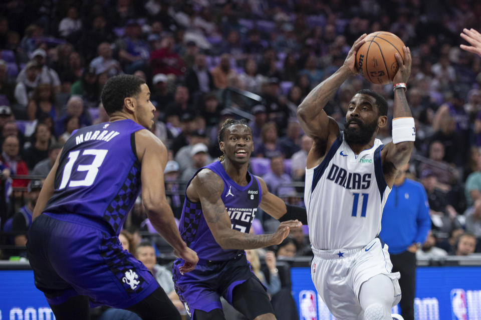 'Dallas Mavericks guard Kyrie Irving (11) drives to the basket as Sacramento Kings forward Keegan Murray (13) and guard Keon Ellis (23) defend during the first half of an NBA basketball game in Sacramento, Calif., Tuesday, March 26, 2024. (AP Photo/José Luis Villegas)