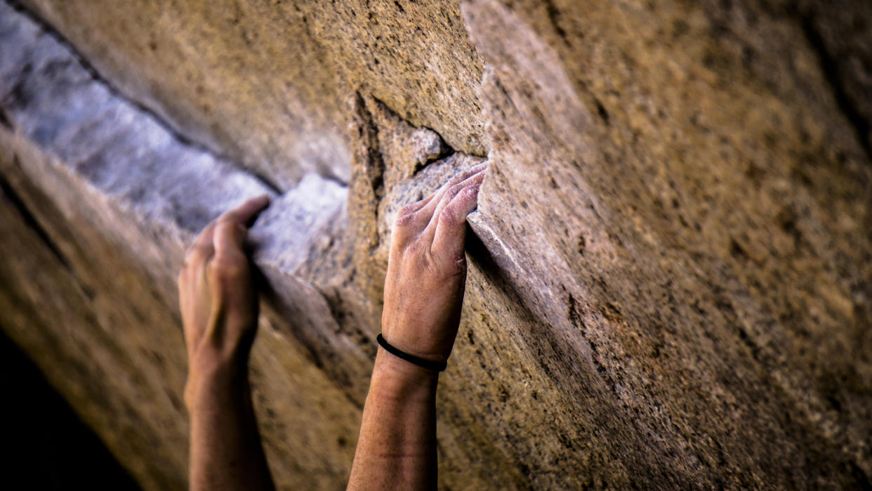  Rock climber's hands on a the famous bouldering roblem Iron Man Traverse in Bishop, California 