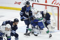 Vancouver Canucks' Matthew Highmore (15) attempts to tip the puck past Winnipeg Jets goaltender Connor Hellebuyck (37) as Nathan Beaulieu (28) defends during the first period of an NHL hockey game, Thursday, Jan. 27, 2022 in Winnipeg, Manitoba. (John Woods/The Canadian Press via AP)