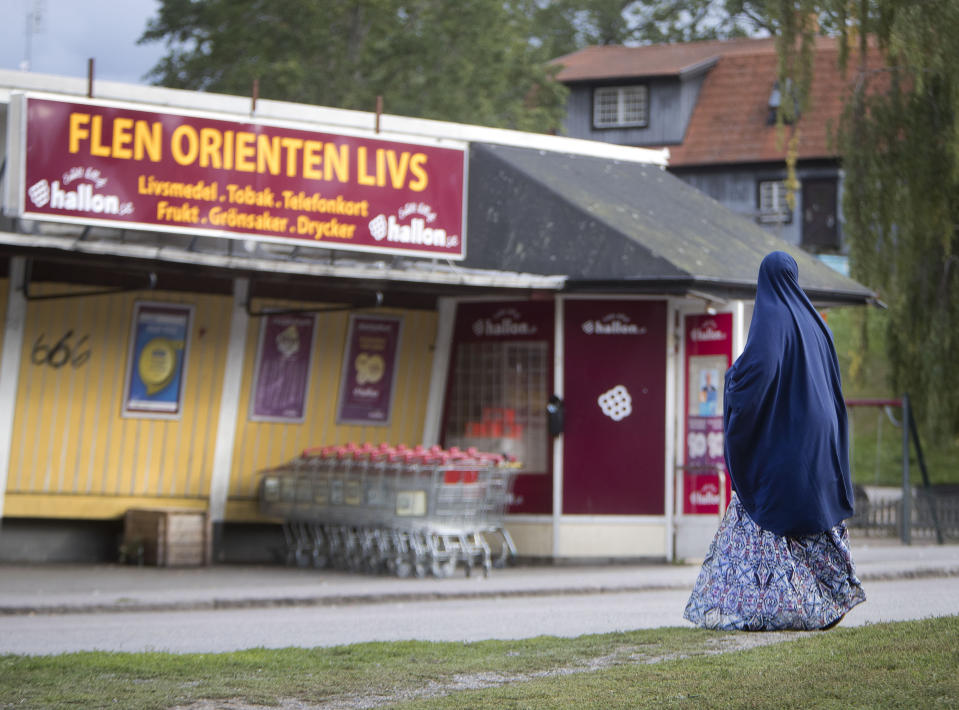 In this Aug. 30, 2018 photo a migrant woman stands in front of an orient supermarket in Flen, some 100 km west of Stockholm, Sweden. The town has welcomed so many asylum seekers in recent years that they now make up about a fourth of the population. (AP Photo/Michael Probst)